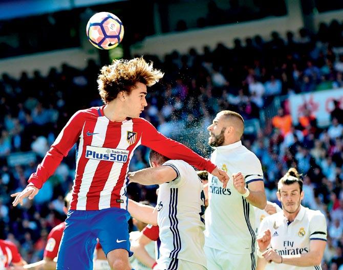 Atletico’s Antoine Griezmann (left) in an aerial tussle for the ball