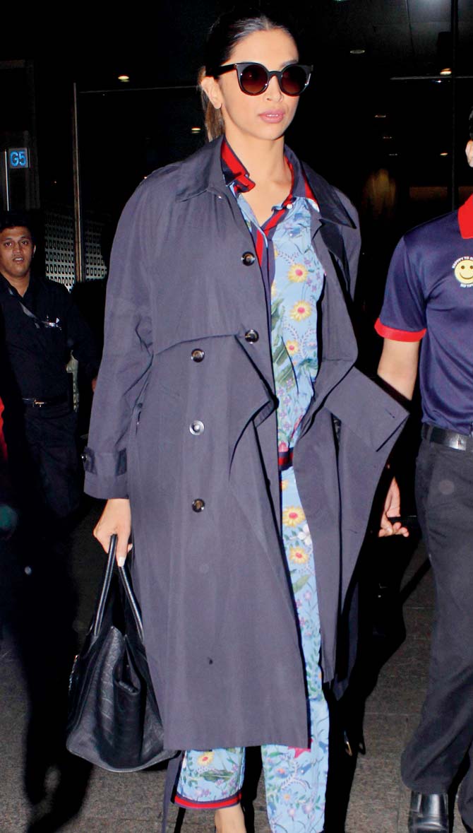 Deepika Padukone does airport chic in a trench coat and a Gucci pyjama set. Pic/Yogen Shah
