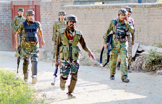 Army soldiers take positions outside a house where the militants were hiding. Pics/PTI
