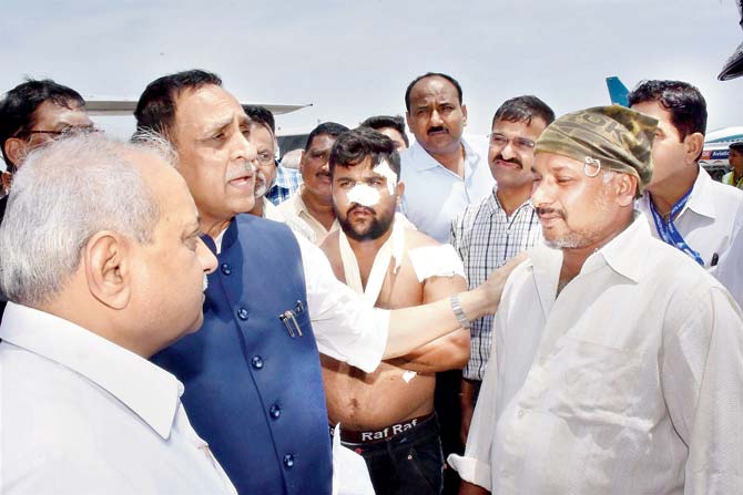 Gujarat Chief Minister Vijay Rupani and deputy CM Nitin Patel interact with the driver of the bus, Salim Sheikh, that was attacked