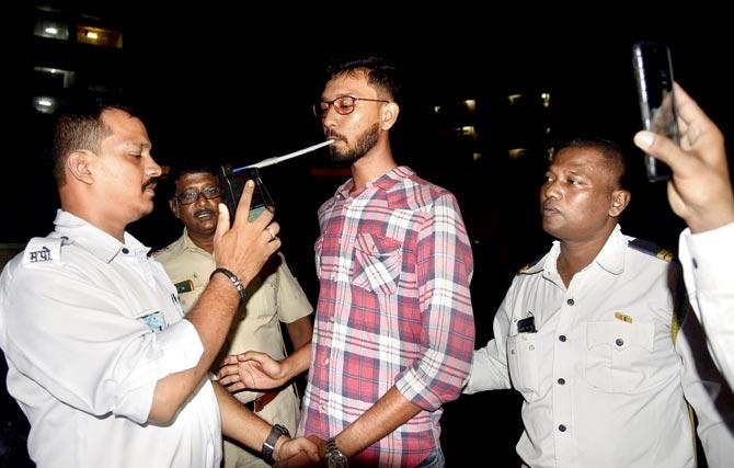 Drunk biker Yusuf Amjad seen undergoing the breath analyser test, minutes after injuring constable Shailesh Pawar (left)