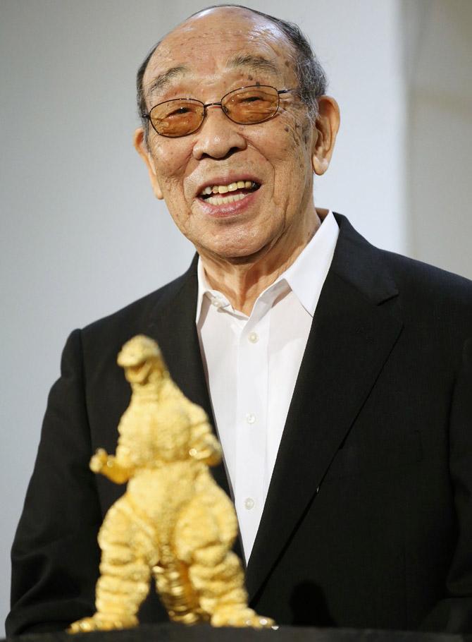 In this picture taken on July 19, 2014, Japanese actor Haruo Nakajima speaks behind a gold statue of Godzilla at a Godzilla exhibition in Tokyo. Nakajima, the actor who played Japan