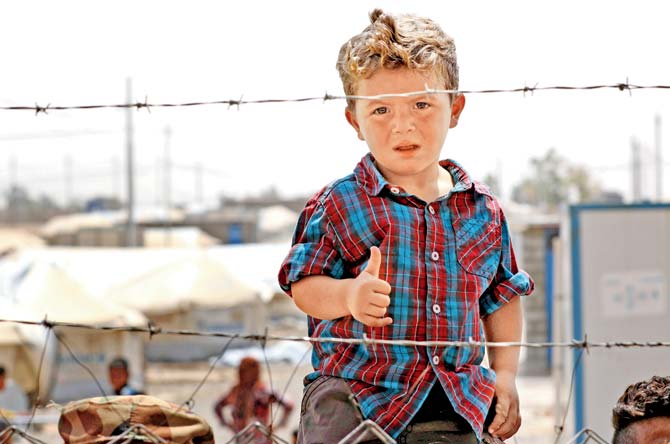 A displaced Iraqi boy, who fled the fighting in Mosul, gestures to the camera at Debaga camp. Pics/AFP