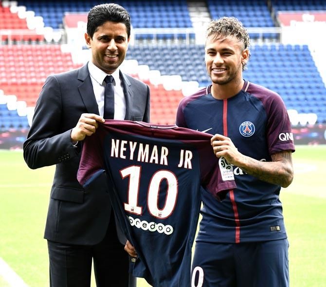 Brazilian superstar Neymar (R) poses with his jersey next to Paris Saint Germain