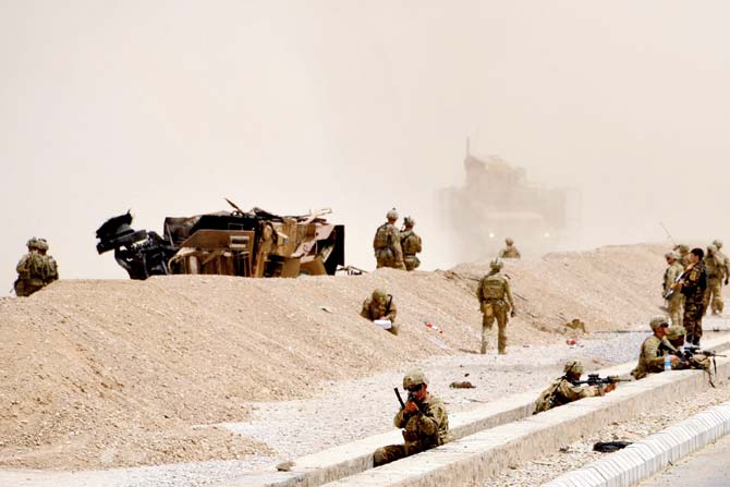 US soldiers keep a watch near the wreckage of their vehicle at the site of the Taliban suicide attack in Kandahar. Pic/AFP