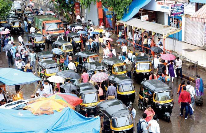 Office-goers scramble for authorickshaws outside the railway station during rursh hour