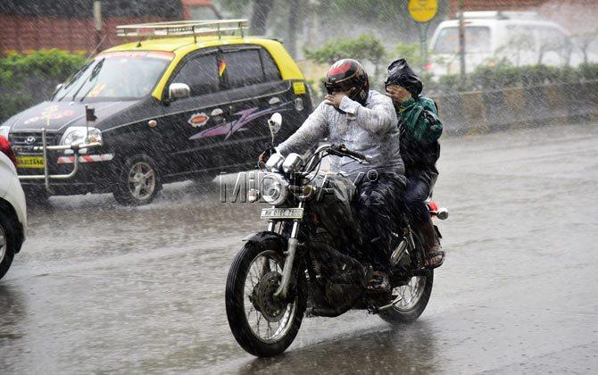 Commuters riding through a rain-lashed street in Mumbai on Saturday. Pic/Sameer Markande