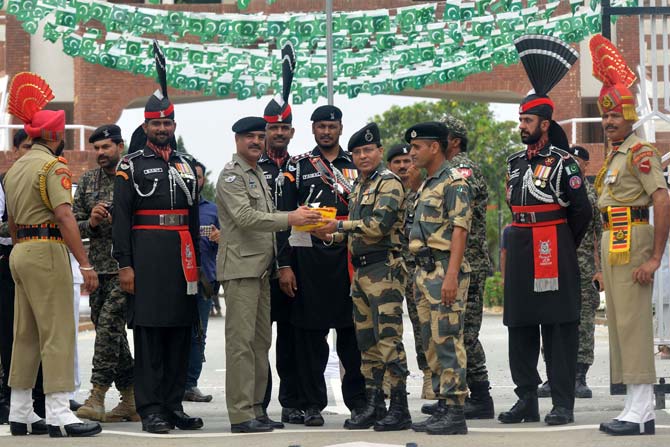 Pakistani Wing Commander presents sweets to Indian BSF Commandant during a ceremony to celebrate Pakistan