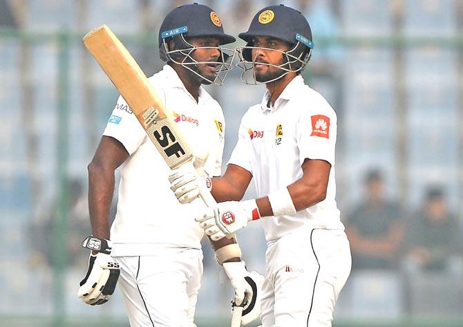 Sri Lanka team captain and batsman Dinesh Chandimal R raises his bat after he completes his half century 50 runs as teammate Angelo Mathews looks on during the third day of the third Test cricket match between India and Sri Lanka at the Feroz Shah Kotla Cricket Stadium in New Delhi. Pic/PTI