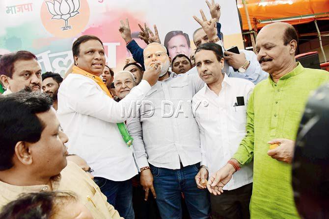 Ashish Shelar feeds sweets to worker wearing a Modi mask outside the party