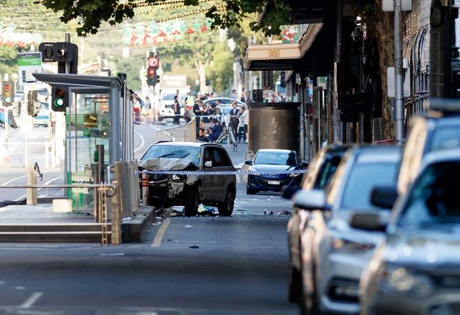 A white SUV (C) sits in the middle of the road as police and emergency personnel work at the scene of where a car ran over pedestrians in Flinders Street in Melbourne. Pic/AFP
