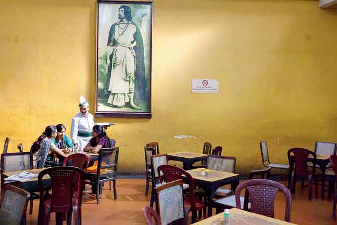 A waiter serves schoolgirls beneath a portrait of Rabindranath Tagore in the Indian Coffee House, Kolkata, 2013. All photographs Stuart Freedman/Courtesy Tasveer