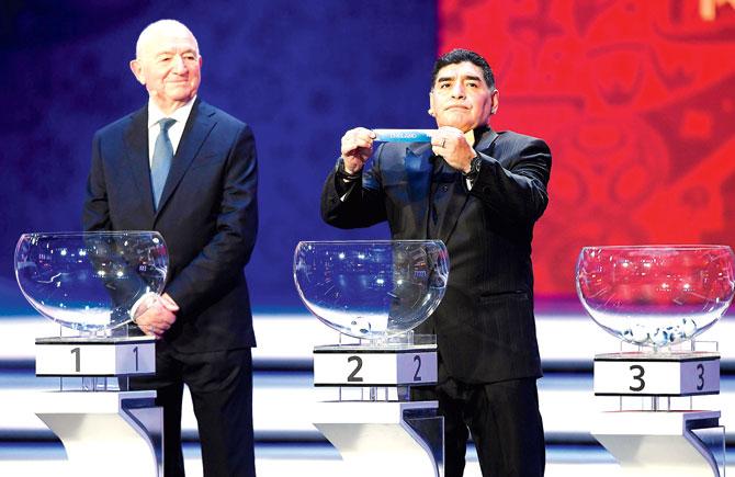 Former Argentina midfielder Diego Maradona right draws a group position as ex-USSR forward and coach Nikita Simonyan looks on during the official draw of 2018 FIFA World Cup in Moscow, Russia yesterday. The mega event will be held in June-July next year. Pic/Getty Images