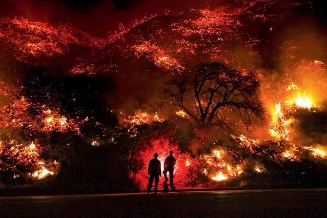 Firefighters monitor a section of the Thomas Fire along the 101 freeway. Pic/AFP