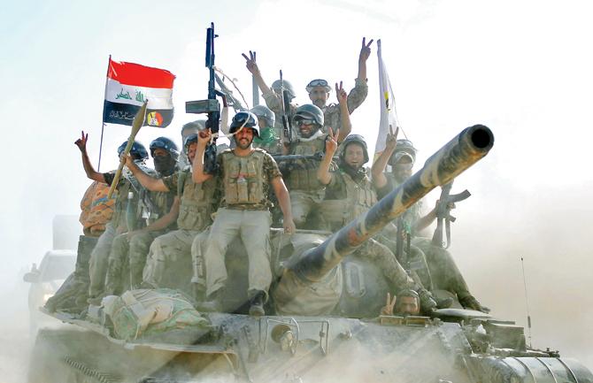 Iraqi troops celebrate after capturing a city from IS. pic/afp