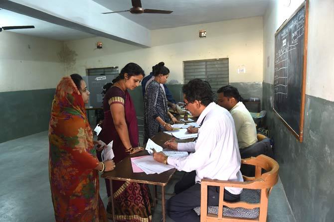 Indian polling officials (R) verify electoral docments of Indian voters in a re-polling centre at Nava Naroda on the outskirts of Ahmedabad. Pic/AFP
