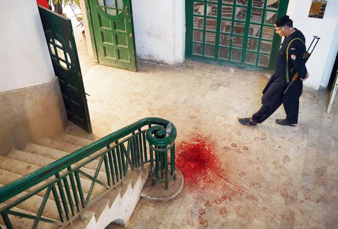 A Pakistani policeman looks at a blood-stained floor of the institute. Pics/AFP