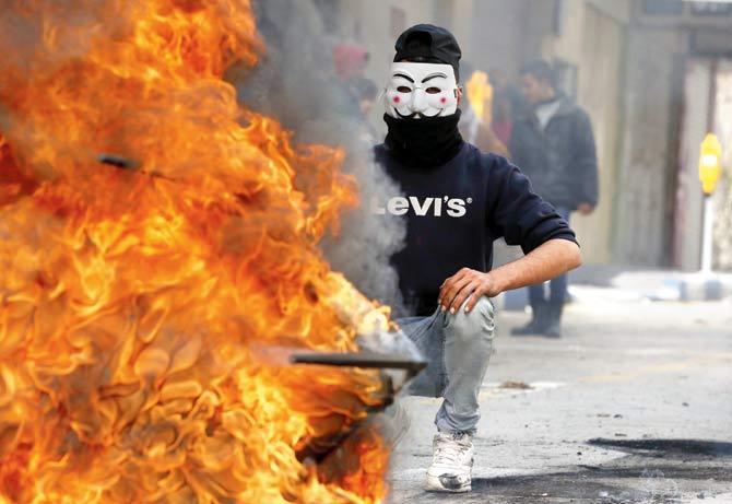 A Palestinian protester wears a Guy Fawkes mask used by the anonymous movement during clashes with Israeli troops on December 7 in Hebron, in the Israeli-occupied West Bank. Pic/AFP