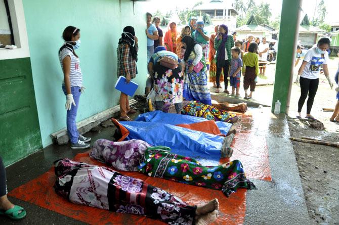 This photo taken on December 23, 2017 shows people looking a the bodies of victims who died during Tropical Storm Tembin in Lanao del Norte on the southern Philippine island of Mindanao. Tens of thousands have been forced from their homes by a tropical storm that battered the southern Philippines leaving at least 182 dead, police and aid agencies said on December 24. Pic/AFP