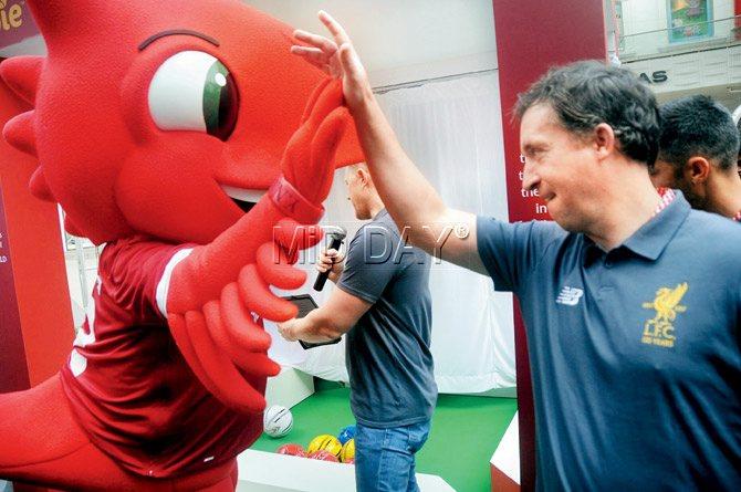 Liverpool great Robbie Fowler high fives the club mascot during  an event in the city yesterday. pic/SAYYED SAMEER ABEDI
