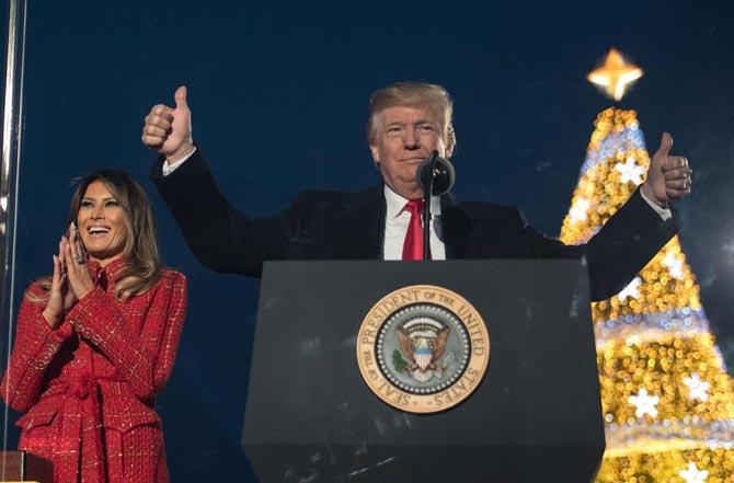 US President Donald Trump (R) gestures as First lady Melania Trump smiles during the 95th annual National Christmas Tree Lighting ceremony at the Ellipse in President