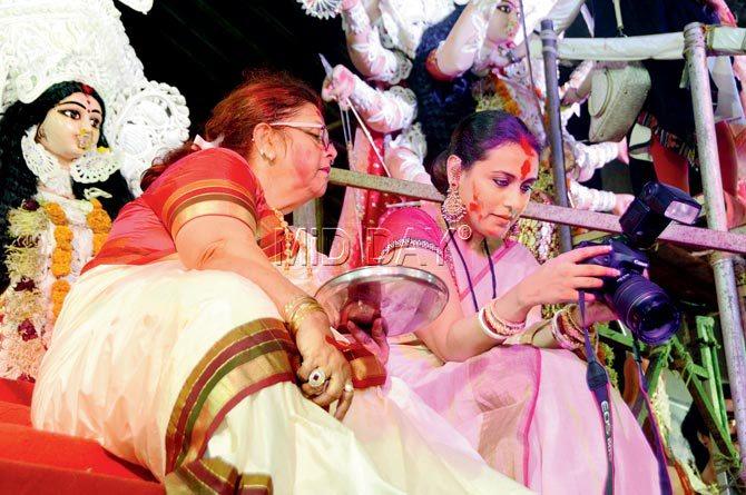 Rani Mukherjee and mother Krishna Mukherjee take a breather to look at some photos during the sindur khela ceremony on the last day of Durga Puja at Juhu
