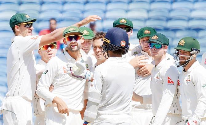 Australian players celebrate the fall of an Indian wicket on Day 2 of the first Test at Maharashtra Crikcet Association Stadium at Pune yesterday 