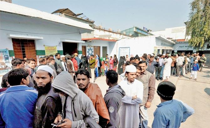 Voters queued up outside a polling booth to cast their votes at Dharampur constituency in Dehradun. Pic/PTI