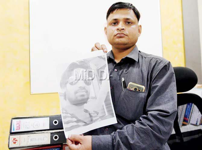 Manjeet Yadav holds up a picture of his cousin, Amit Yadav, who died after a 13-ft wave hit his ship. Pics/Suresh Karkera