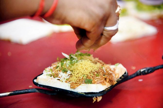 A staffer garnishes the bhel sandwich before toasting it