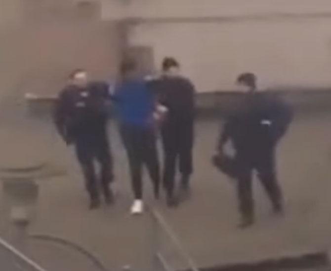 Theo being escorted to the police car after being arrested