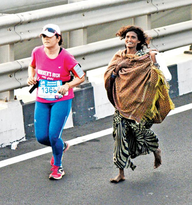 A rag picker runs alongside a participant during the 2017 Mumbai Marathon yesterday