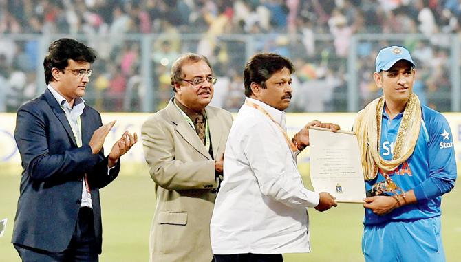 Mumbai Cricket Association’s Joint Secretary Dr PV Shetty presents a citation to MS Dhoni (right) as former India skipper and CAB chief Sourav Ganguly (left) looks on at the Eden Gardens yesterday. Pic/PTI