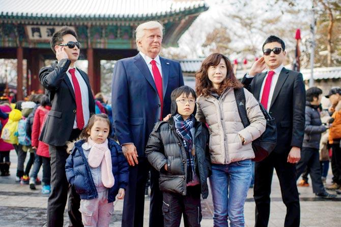 Pedestrians pose with a waxwork figure of US President-elect Donald Trump prepared to be placed on a street in Seoul, S Korea. Most Asian markets turned lower with nervous investors awaiting the Trump effect. Pic/AFP
