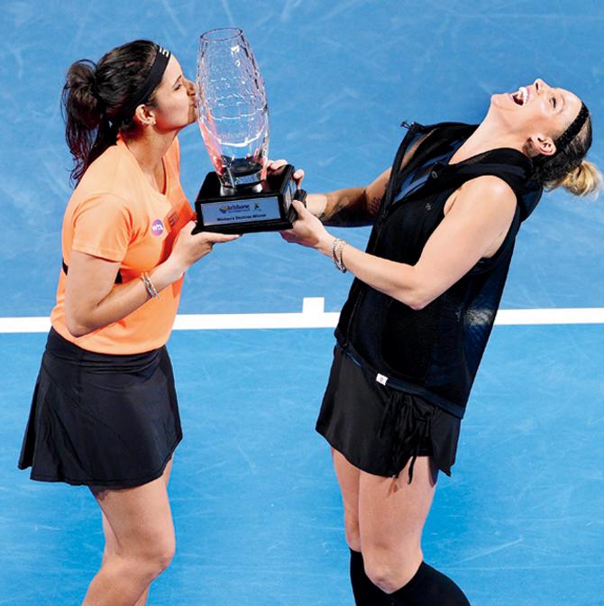 Sania Mirza (left) kisses the Brisbane International winners’ trophy as Bethanie Mattek-Sands looks ecstatic on Saturday. Pic/AFP