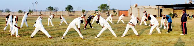 Saurashtra middle-order batsman Arpit Vasavada (centre, in tracksuit) guides the youngsters during a warm-up session at Cheteshwar Pujara Cricket Academy in Rajkot as Bipin Pujara (extreme right) looks on 