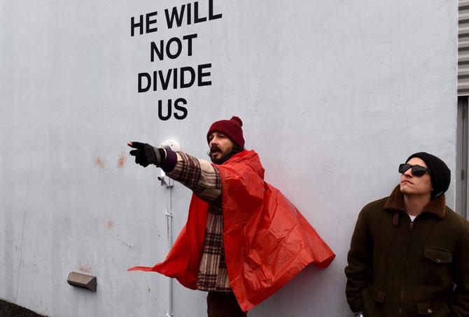 US actor Shia LaBeouf(L) during his “He Will Not Divide Us” livestream outside the Museum of the Moving Image in Astoria, in the Queens borough of New York January 24, 2017 as a protest against President Donald Trump. LaBeouf has installed a camera at the Museum of the Moving Image in New York that will run a continuous live stream for the duration of Trump’s presidency. LaBeouf is inviting the public to participate in the project by saying the phrase, “He will not divide us,” into the camera. Pic/AFP