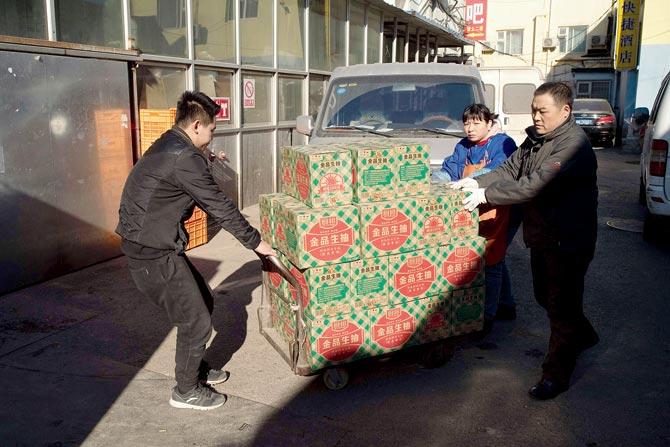 Workers transfer goods from a van to a supermarket in Beijing. Beijing is bracing for an uncertain outlook that could see a trade stand-off with Donald Trump. Pic/AFP