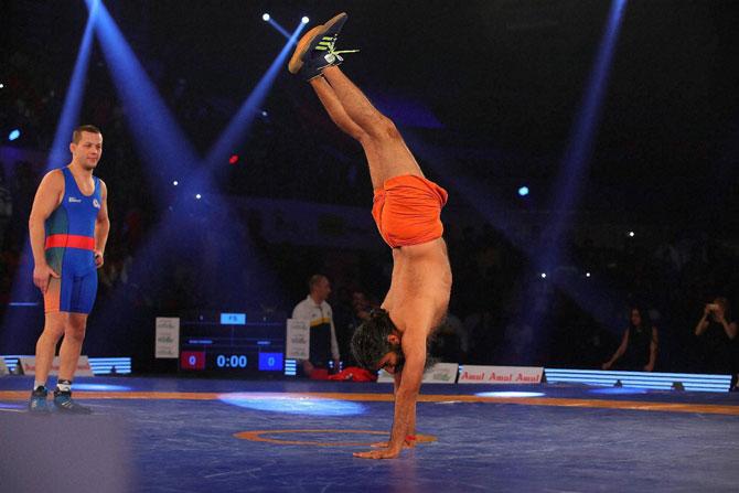 Baba Ramdev displayed his yoga skills as Olympic medalist Andrey Stadnik looks on during friendly wrestling bout ahead of second semifinal match between Mumbai Maharathi and NCR Punjab Royals, in the Pro Wrestling League in New Delhi on Wednesday.PTI 