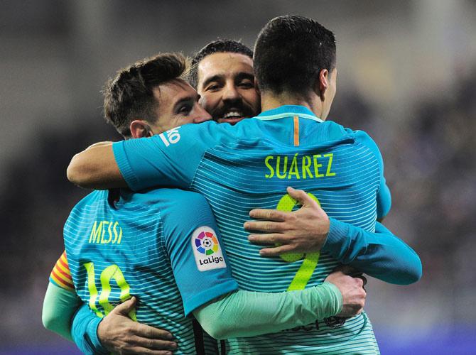 Luis Suarez (R) is congratulated by teammates Argentinian forward Lionel Messi (L) and Turkish midfielder Arda Turan after scoring