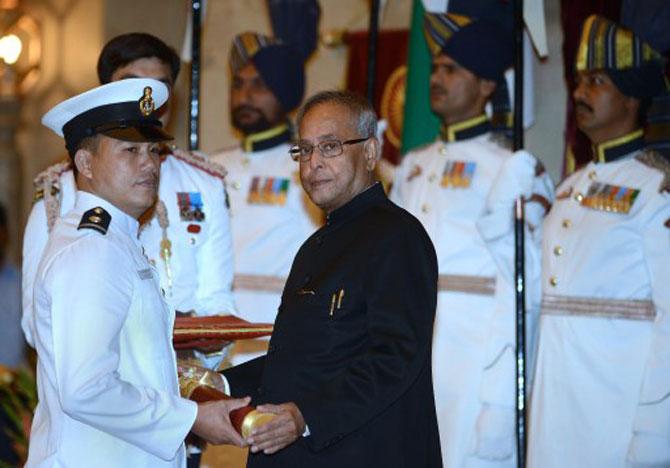 Indian President Pranab Mukherjee (R) presents the Padma Shree award to the Chief Coach of the Indian Navy boxing team, Ngangom Dingko Singh during the presentation of the 