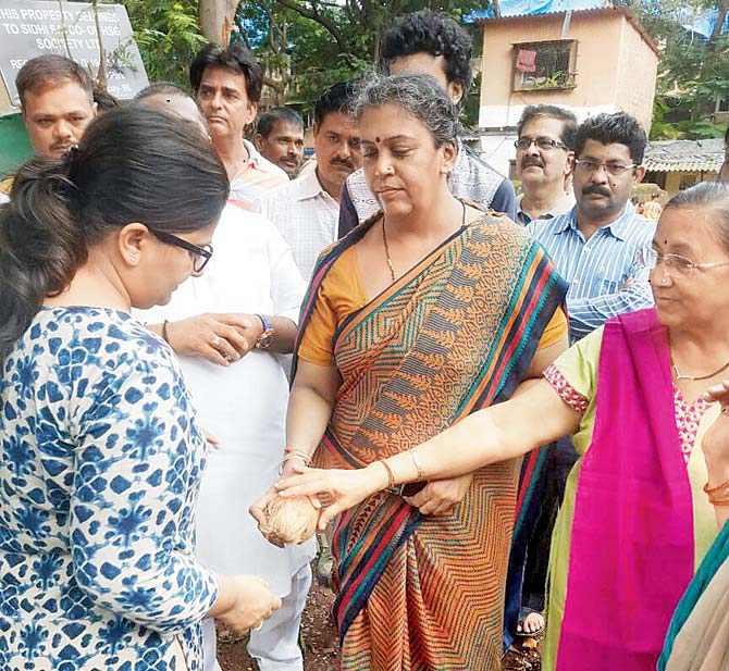 Residents break a coconut during the bhoomi pujan for the building