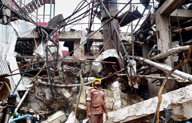 Bangladeshi firefighters at the destroyed garment factory. Pic/AFP