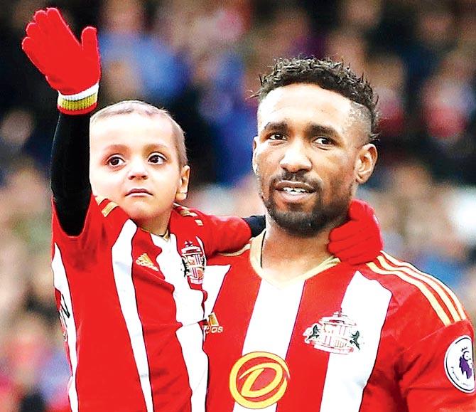 Former Sunderland FC star Jermain Defoe wipes his tears at the funeral ceremony of Bradley Lowery (left) yesterday