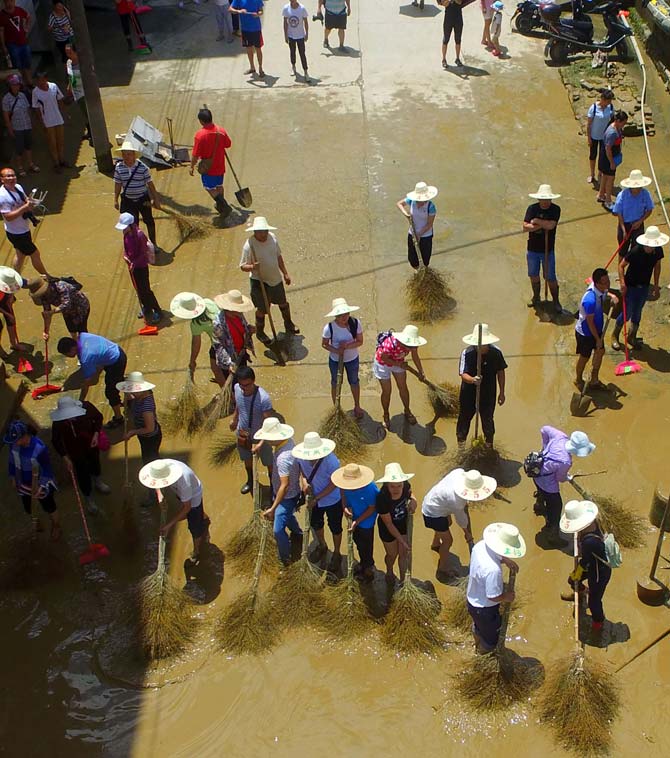 People cleaning a flooded street in Luizhou, Guangxi province. Rainstorms have triggered floods across central and southern China. Pic/AFP