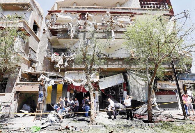 Syrians inspect the damage at the site of the suicide bomb attack in the capital. Pic/AFP