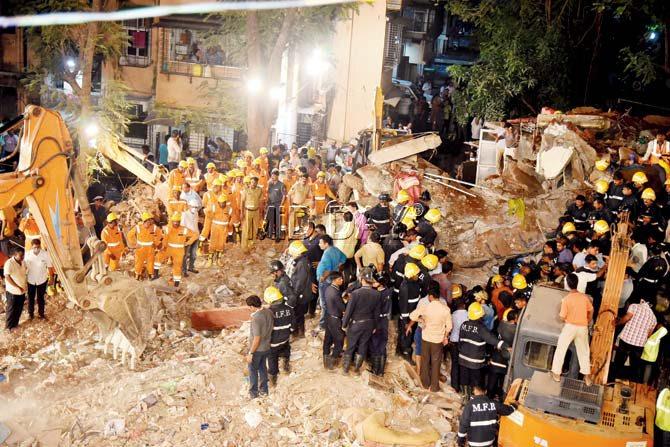 This photo taken at 10.10 pm on Tuesday shows the stand-off between personnel of the National Defence Rescue Force on the left in orange suits, and the men of the Mumbai Fire Brigade on the right in blue. The victim, who remained buried alive at the time of going to press, is not seen in the photo. Pic/Shadab Khan