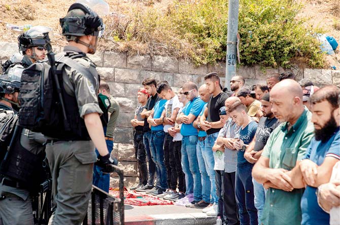 Israeli security forces stand guard as Palestinian worshippers pray outside Jerusalem