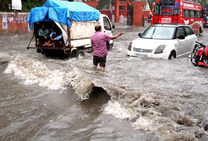 Vehicles make their way through flooded street after heavy rains in Jammu. Pic/PTI