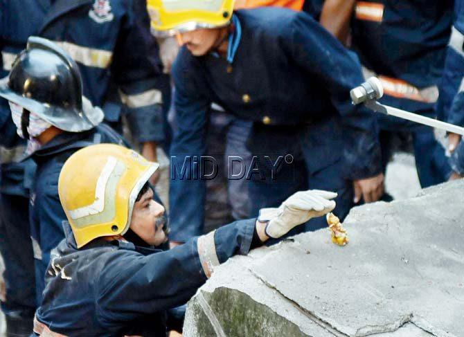 Perhaps hoping for some help from the almighty, a fireman of the Mumbai Fire Brigade gingerly places an idol of Lord Ganesha recovered from the debris during rescue work at the site where the four-storeyed Siddhi Sai Apartment collapsed. Pic/Shadab Khan